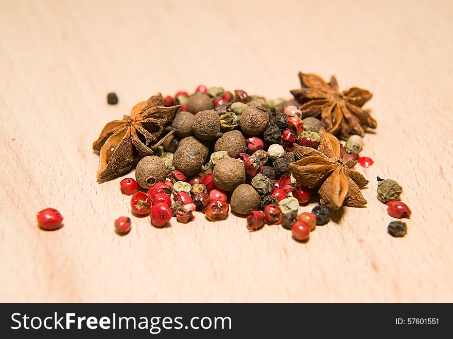 A mixture of grains of pepper and star anise on a wooden surface