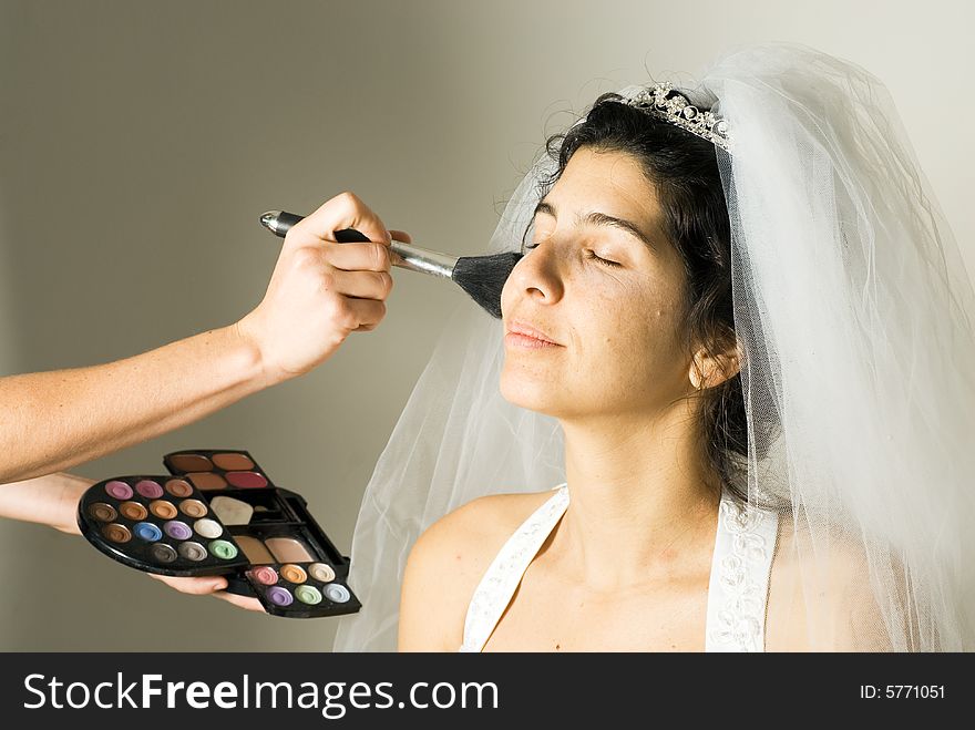 A woman in a wedding dress, sits patiently, getting her make-up done. - horizontally framed. A woman in a wedding dress, sits patiently, getting her make-up done. - horizontally framed