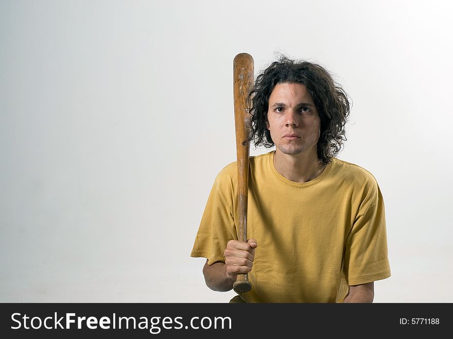 A man holding a  baseball bat and sitting on the floor with a serious look on his face. Horizontally framed photograph. A man holding a  baseball bat and sitting on the floor with a serious look on his face. Horizontally framed photograph