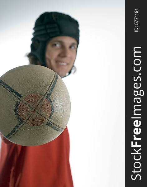 Man with an outstretched arm wearing a helmet holds a rugby football and smiles. Vertically framed photograph. Man with an outstretched arm wearing a helmet holds a rugby football and smiles. Vertically framed photograph