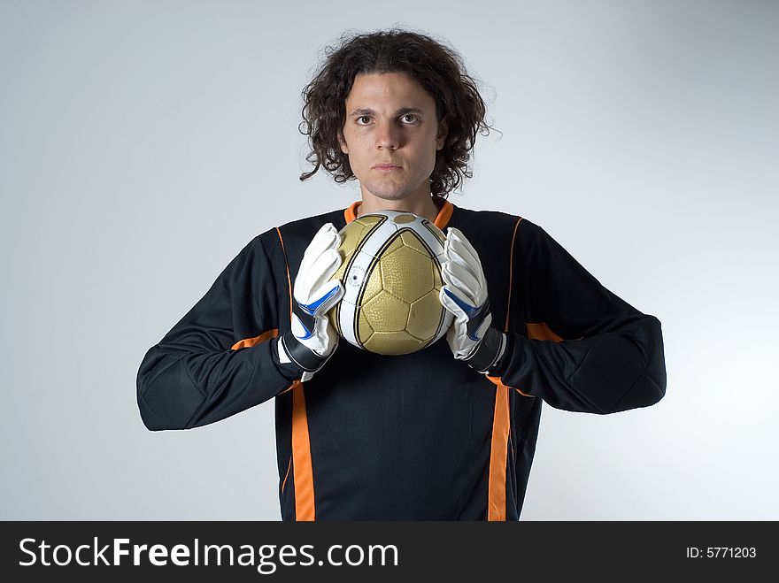 Soccer goalie holds a soccer ball with his goalie gloves and has a serious expression on his face. Horizontally framed photograph. Soccer goalie holds a soccer ball with his goalie gloves and has a serious expression on his face. Horizontally framed photograph