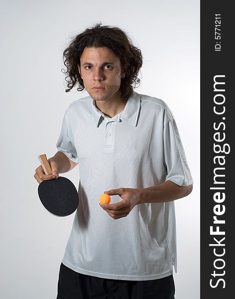 Man standing up holding a ping pong ball and a paddle. He has a serious expression on his face. Vertically framed photograph. Man standing up holding a ping pong ball and a paddle. He has a serious expression on his face. Vertically framed photograph