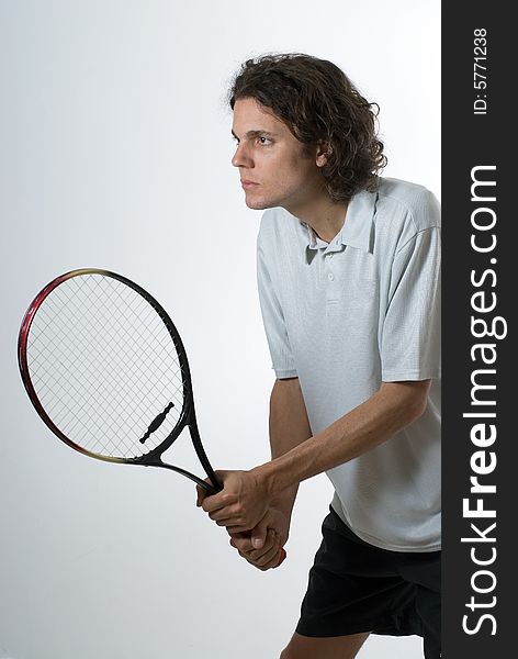 A tennis player holding a racket and staring intensely into the unseen distance. Vertically framed shot. A tennis player holding a racket and staring intensely into the unseen distance. Vertically framed shot.