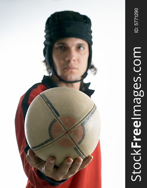 Man with an outstretched arm wearing a helmet holds a rugby football and looks serious. Vertically framed photograph. Man with an outstretched arm wearing a helmet holds a rugby football and looks serious. Vertically framed photograph