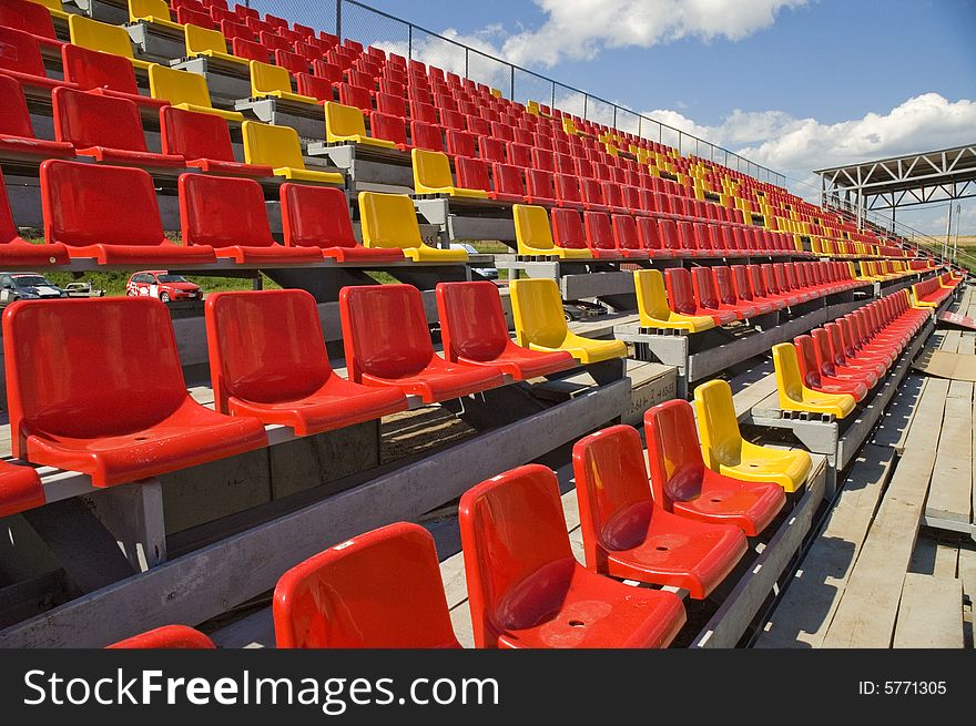 Red and yellow seats on a background of the sky with clouds. Red and yellow seats on a background of the sky with clouds.