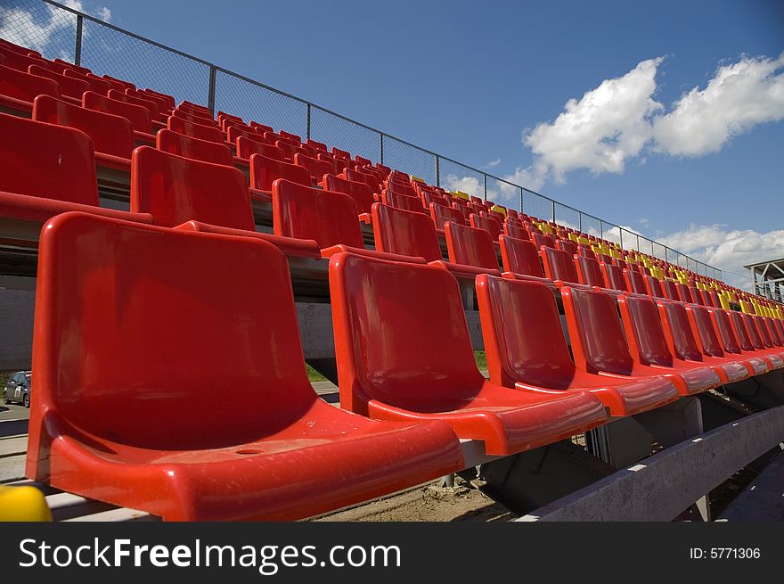 Red seats on a background of the sky with clouds. Red seats on a background of the sky with clouds.