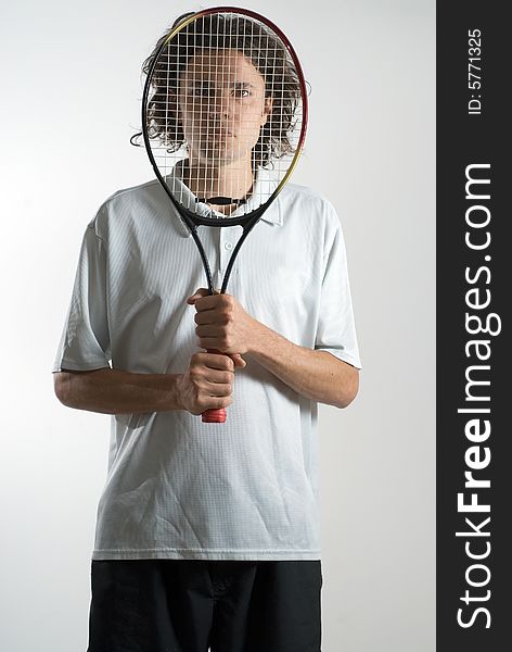 Man holds a tennis racket in front of his face and has a serious expression. Vertically framed photograph. Man holds a tennis racket in front of his face and has a serious expression. Vertically framed photograph