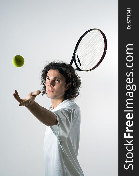 An action shot of a tennis player serving a tennis ball. The ball is in the air, and the model is staring at it. Vertically framed shot. An action shot of a tennis player serving a tennis ball. The ball is in the air, and the model is staring at it. Vertically framed shot.