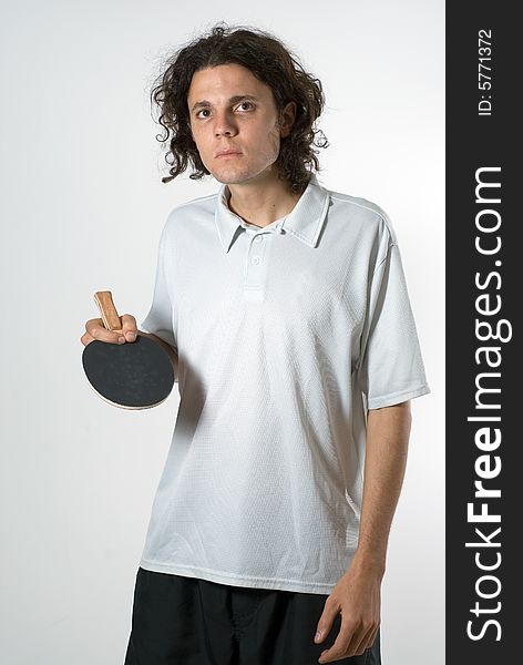 A young man holding a ping-pong paddle. He is holding the paddle between his index finger and thumb and he is looking intensely at the camera. Vertically framed shot. A young man holding a ping-pong paddle. He is holding the paddle between his index finger and thumb and he is looking intensely at the camera. Vertically framed shot.