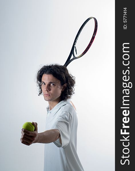 Man holds a tennis ball in one hand and a tennis racket in the other. He has a serious look on his face. Vertically framed photograph. Man holds a tennis ball in one hand and a tennis racket in the other. He has a serious look on his face. Vertically framed photograph