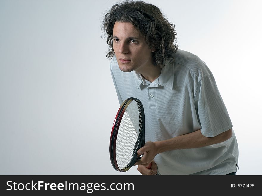 A young man, stands in a ready stance, looking anxious, getting ready to play tennis. Horizontally framed shot. A young man, stands in a ready stance, looking anxious, getting ready to play tennis. Horizontally framed shot.