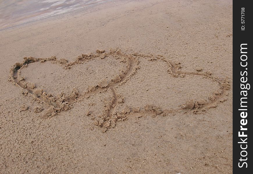 Figure of two hearts on sand of a beach