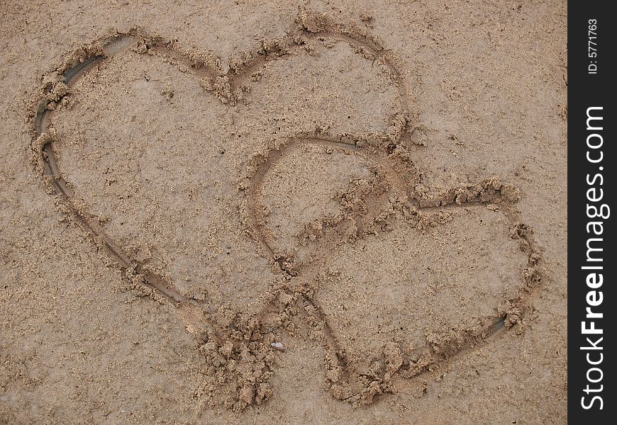 Figure of two hearts on sand of a beach