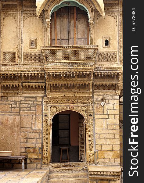 Detail of an old carved and sculpted yellow sand stone mogul style dwelling with pillars arches and balcony constructed at the time of Maharajahs by a rich merchant. Rajasthan, India. Detail of an old carved and sculpted yellow sand stone mogul style dwelling with pillars arches and balcony constructed at the time of Maharajahs by a rich merchant. Rajasthan, India.