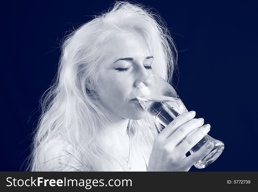 Young blond woman holds glass against the black background. Young blond woman holds glass against the black background.