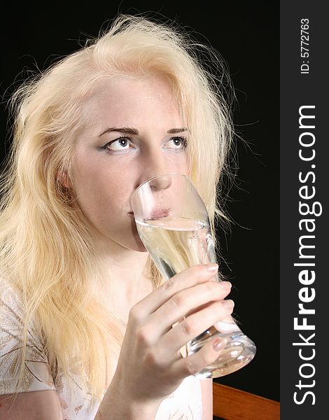 Young blond woman holds glass against the black background. Young blond woman holds glass against the black background.