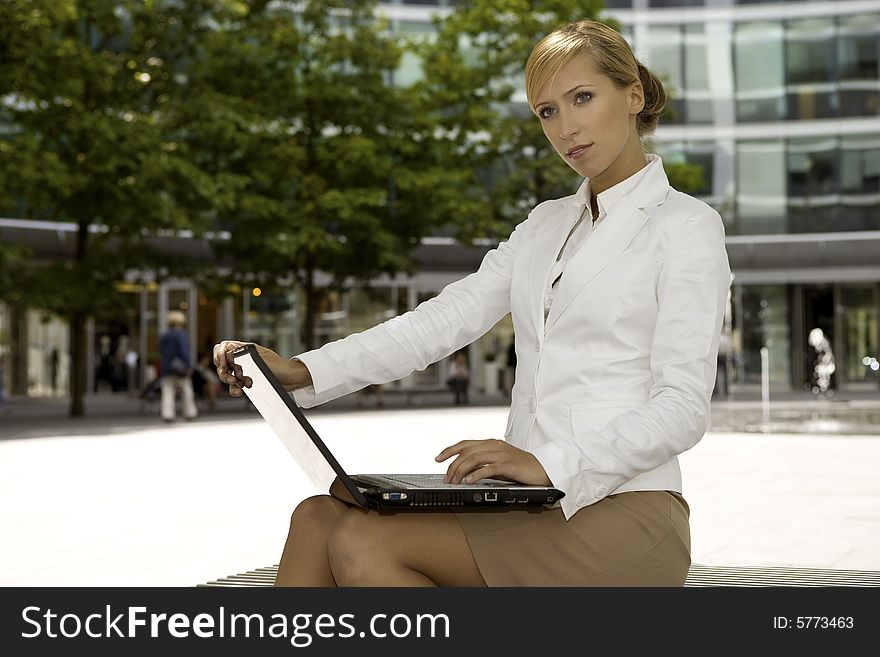 Young and attractive blonde businesswoman working on laptop outdoors. Young and attractive blonde businesswoman working on laptop outdoors