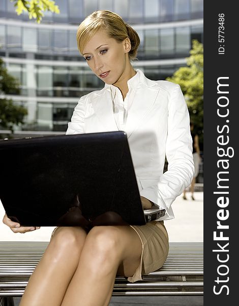 Young and attractive businesswoman working on laptop outdoors. Young and attractive businesswoman working on laptop outdoors
