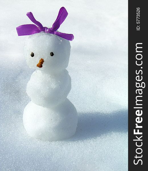 Snowgirl with a bow on a background of a snow. Snowgirl with a bow on a background of a snow