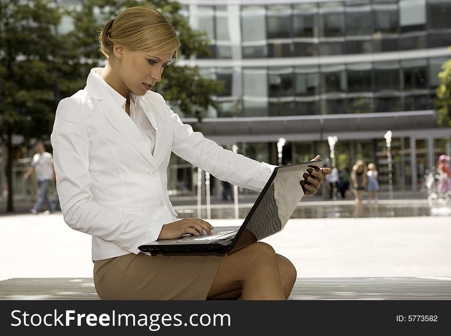 Young and attractive blonde businesswoman working on laptop outdoors. Young and attractive blonde businesswoman working on laptop outdoors