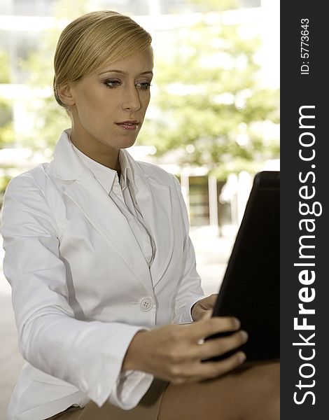 Young and attractive blonde businesswoman working on laptop outdoors. Young and attractive blonde businesswoman working on laptop outdoors