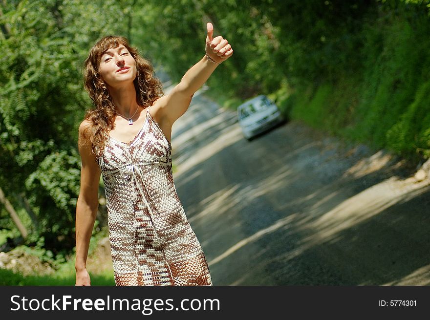 Pretty girl hitching hiking on country road. Pretty girl hitching hiking on country road.