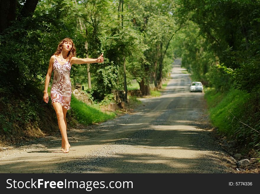 Pretty girl hitching hiking on country road. Pretty girl hitching hiking on country road.