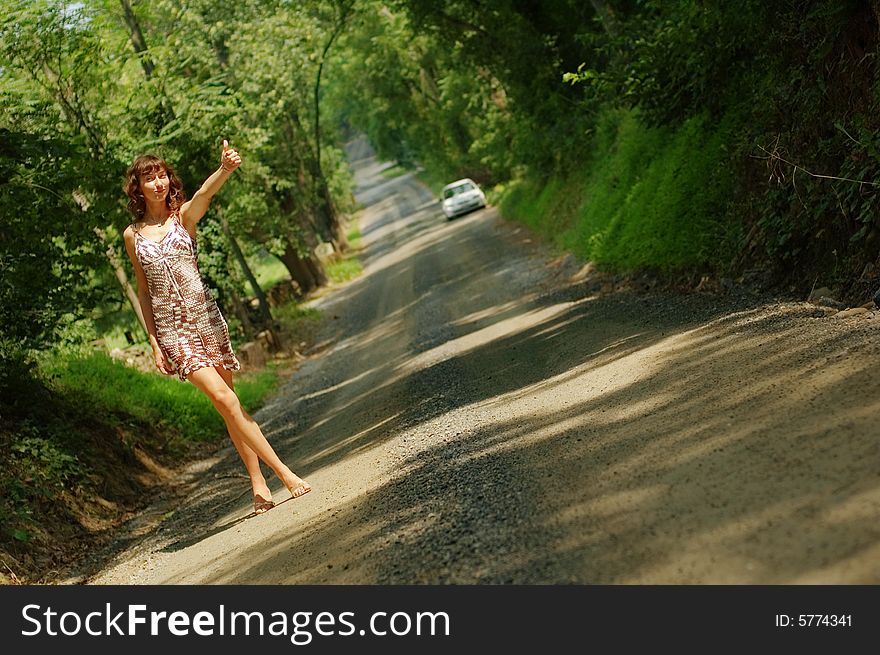 Pretty girl hitching hiking on country road. Pretty girl hitching hiking on country road.