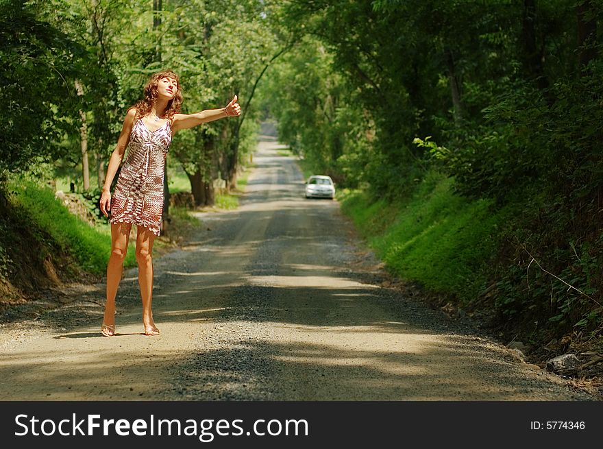 Pretty girl hitching hiking on country road. Pretty girl hitching hiking on country road.