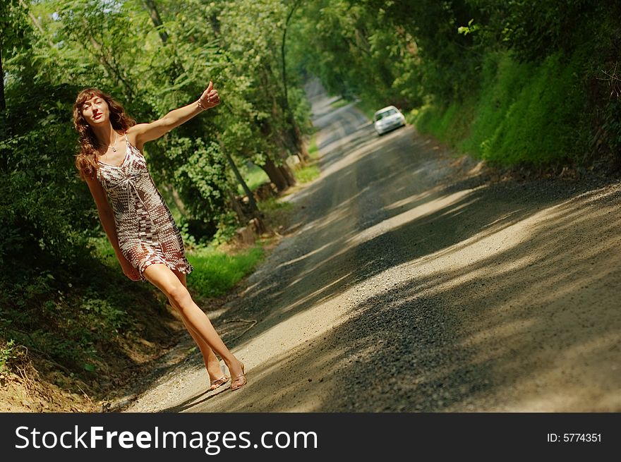 Pretty girl hitching hiking on country road. Pretty girl hitching hiking on country road.