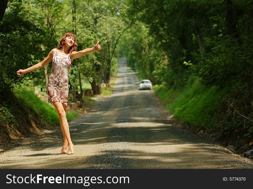 Pretty girl hitching hiking on country road. Pretty girl hitching hiking on country road.