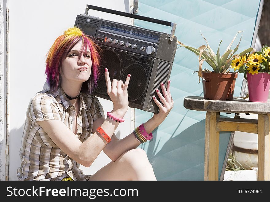 Punk girl with brightly colored hair sitting on trailer step holding boom box. Punk girl with brightly colored hair sitting on trailer step holding boom box