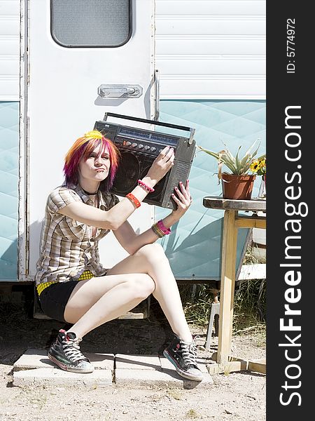 Punk girl with brightly colored hair sitting on trailer step holding boom box. Punk girl with brightly colored hair sitting on trailer step holding boom box