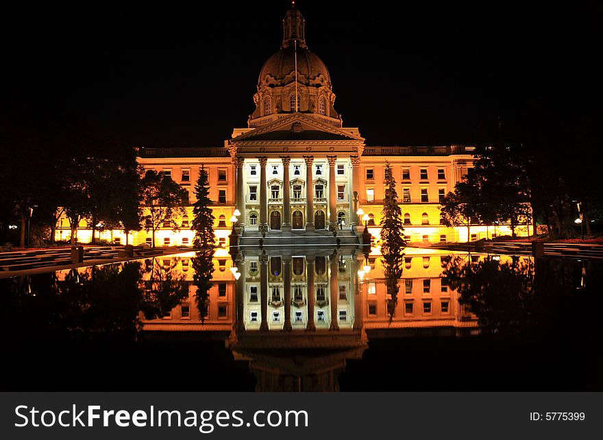 A large government building mirrored in a reflecting pool at night. A large government building mirrored in a reflecting pool at night