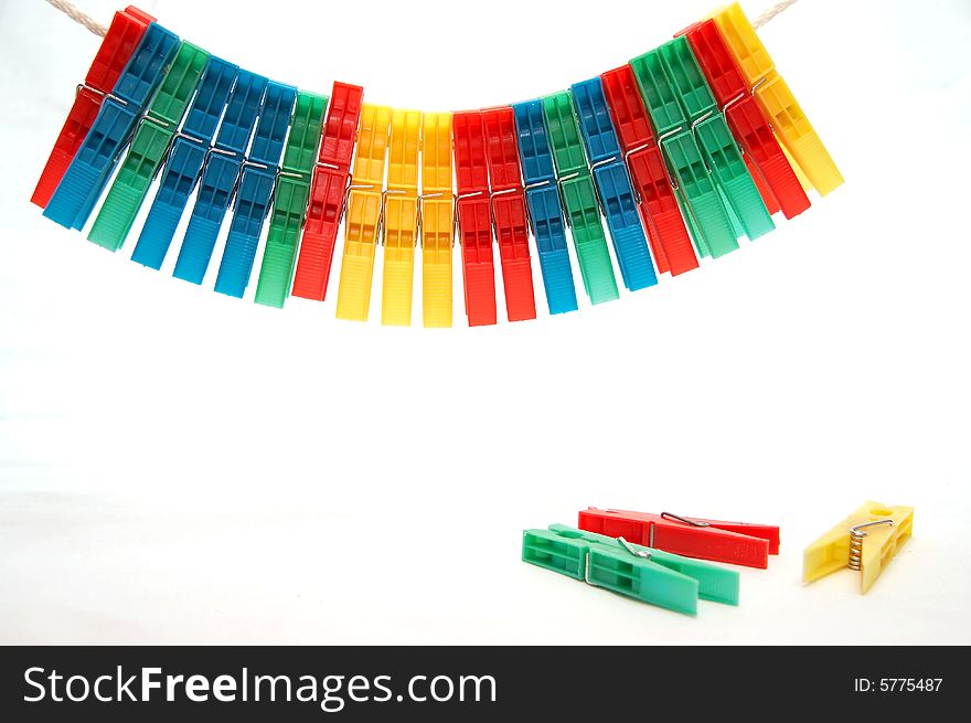 Set of the varicoloured clothes-pegs on rope and several clothes-pegs under him on white background. Set of the varicoloured clothes-pegs on rope and several clothes-pegs under him on white background