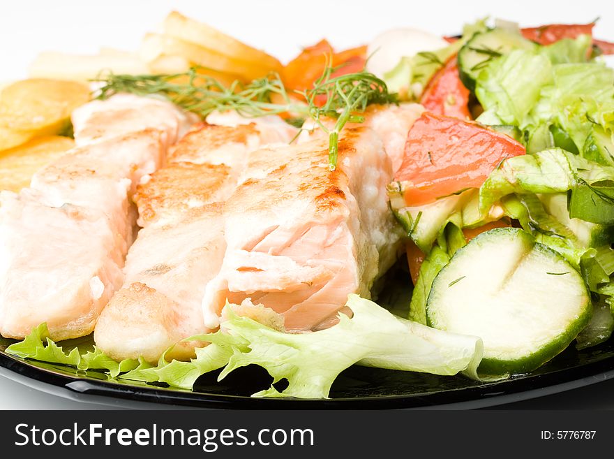 Stake from a salmon with vegetables on a plate. Closeup.