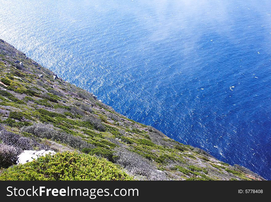 Over the edge of the green precipice lays the blue ocean