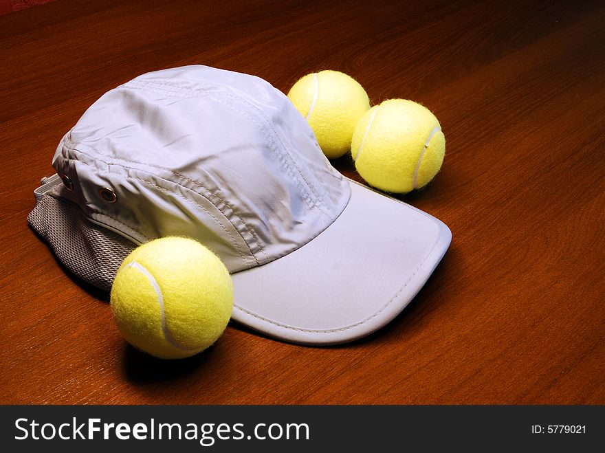Three tennis-balls and a sport-cap. Three tennis-balls and a sport-cap