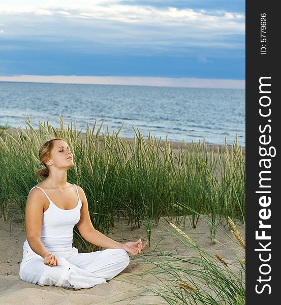 Young cute girl meditating on the beach. Young cute girl meditating on the beach.
