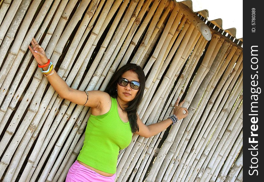 A Indian babe posing in front of a bamboo house