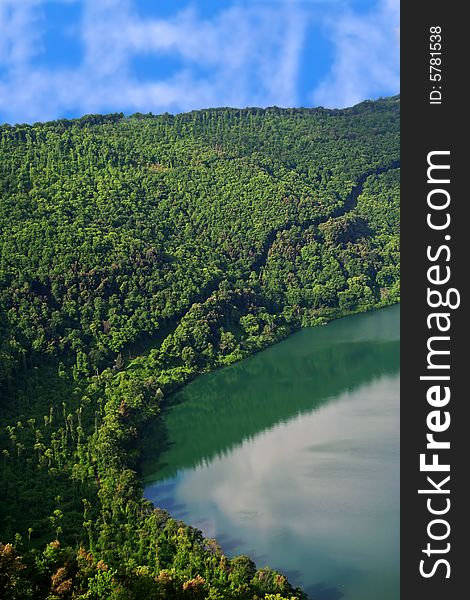 Green mountains with volcanic lake against sunny sky. Green mountains with volcanic lake against sunny sky