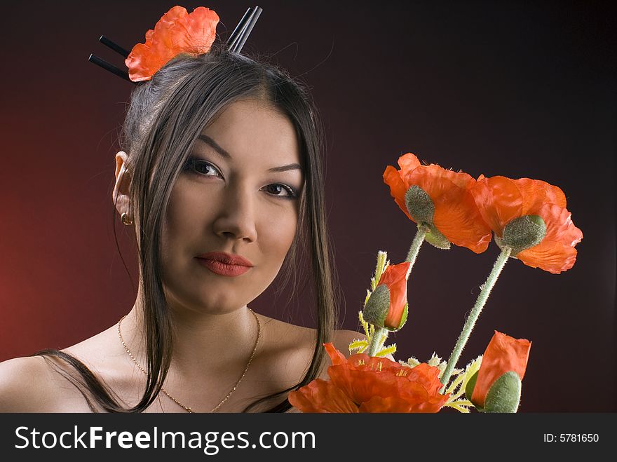 Beautiful young asiatic girl with red poppies against red