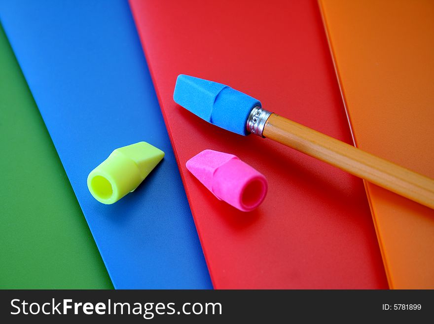 Four colorful folders along with erasers and a pencil. Used a selective focus here with it being on the pencil and blue eraser. Four colorful folders along with erasers and a pencil. Used a selective focus here with it being on the pencil and blue eraser.