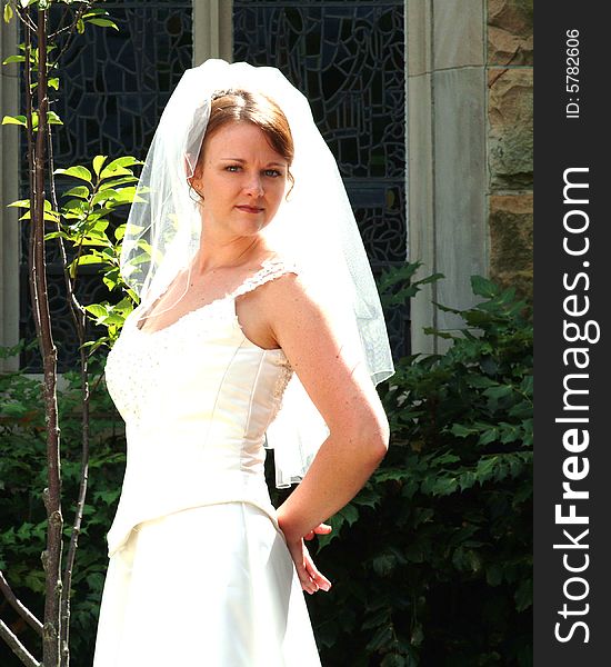 View of bride outside near stained glass window. View of bride outside near stained glass window