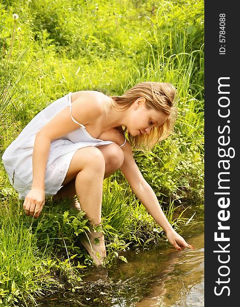 Beautiful blond girl at river in summer
