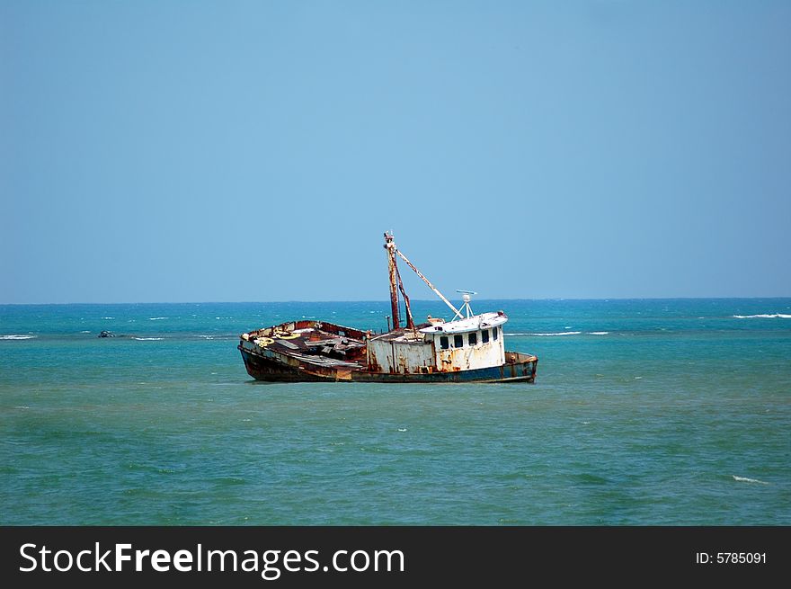 Shipwrecked fishing boat in tropical blue water
