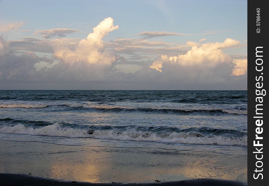 The sea with cloud reflections filled with sunset colours on Cape Canaveral town beach, Florida.