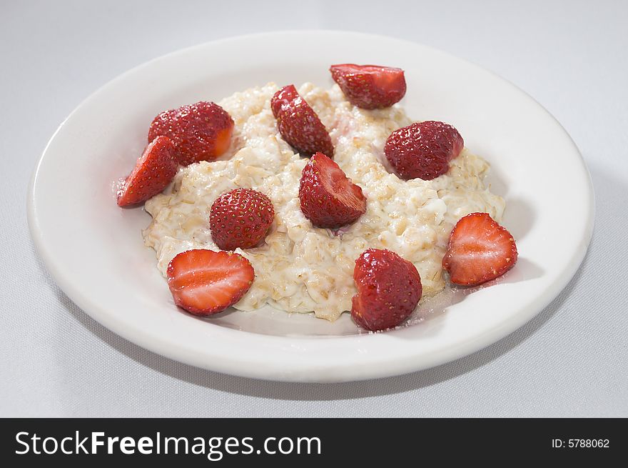 Porridge with slices of berries of a strawberry on a plate