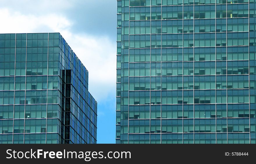 Two buildings with blue green tinted glass against a blue sky. Two buildings with blue green tinted glass against a blue sky.