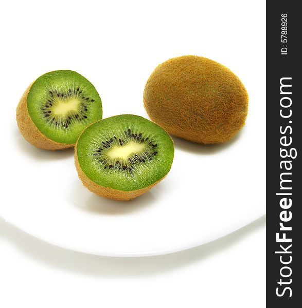 A group of cut and whole kiwis on white plate and isolated on white background. A group of cut and whole kiwis on white plate and isolated on white background